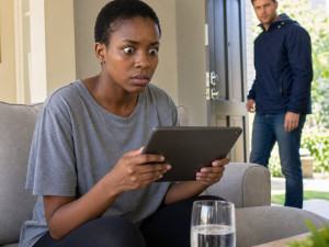 Mara stares at a tablet on the couch as Evan walks in through the front door.