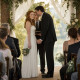 At the altar, the redheaded bride stands tense as the groom leans in smiling, gripping her hand too tightly while the officiant looks startled.